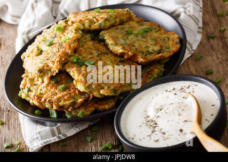 Delicious zucchini pancakes with sour cream close-up on the table. horizontal Stock Photo