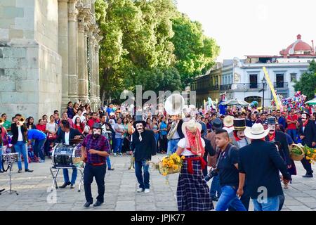 A crowd watches as male dancers in hats and face masks perform traditional dancing in the Zocalo in celebration of the Day of the Dead. Oaxaca, Mexico. Stock Photo