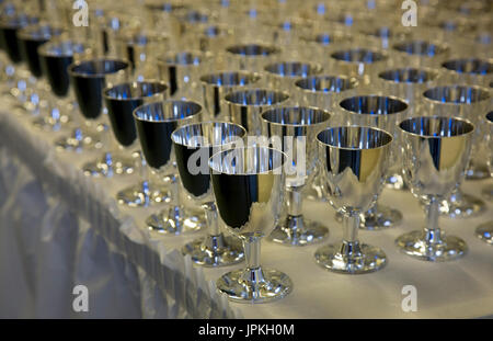 Rows of silver champagne goblets on a table with a white tablecloth to celebrate high school prom Stock Photo