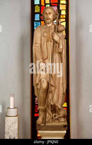Wood carved statue of Saint Roch with plague bubo on thigh and dog with bread that saved him in Saint Roch's Catholic church Toronto Canada Stock Photo