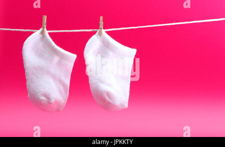 A pair of white baby socks on a clothes line Stock Photo