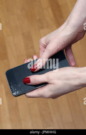 Female hands holding broken smartphone with cracked display Stock Photo