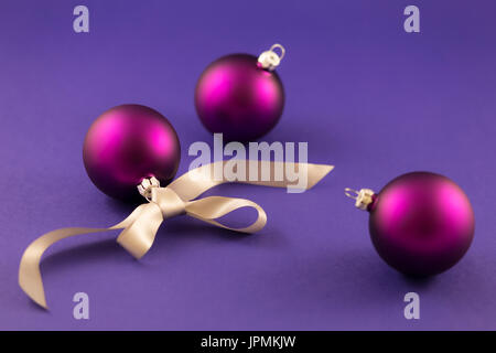 Beautiful purple christmas balls with satin effect and grey gift ribbon on purple background. Stock Photo