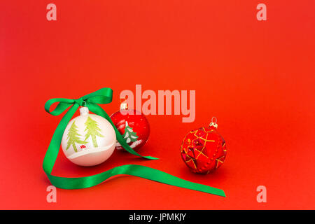 Beautiful white and red christmas balls with green silky ribbon on red background. Stock Photo