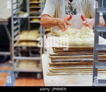 Bakery worker kneading dough by hand in commercial bakery Stock Photo
