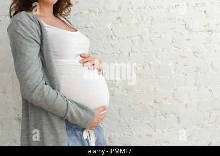 Pregnant woman touching belly close-up on a white background Stock Photo