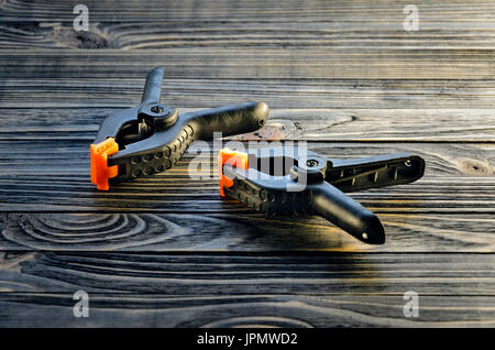 Pair of black clamps with orange plastic jawson on black wood carpenter's bench. Part of the workplace of a carpenter Stock Photo