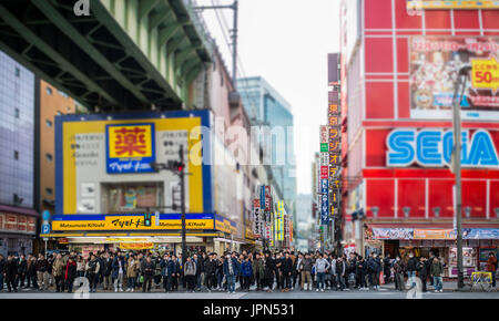 TOKYO, JAPAN - JANUARY 2, 2017: Crowds pass below colorful signs in Akihabara. The historic electronics district has evolved into a shopping area for  Stock Photo