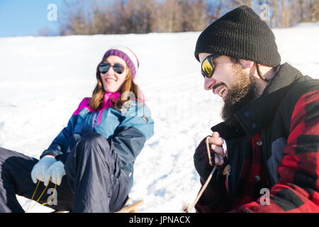 Young couple having fun on the sleds Stock Photo