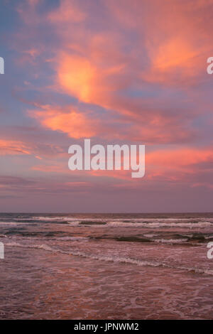 View of Colorful Clouds Over Calm Ocean Waves During Golden Hour Stock Photo