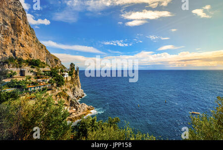 Interesting rock formation with homes and villas on the side of a steep mountain on the Amalfi Coast in Italy as the sun goes down Stock Photo