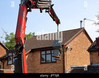 And out she comes, a large Henry Milnes Lathe is lifted from the rear of a property out througha gap between houses to the waiting lorry for transport Stock Photo