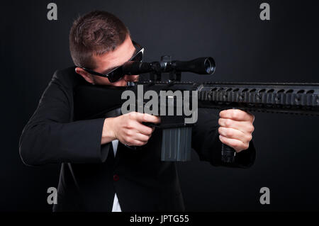 Male killer with sniper rifle aiming one side and getting ready to shoot Stock Photo