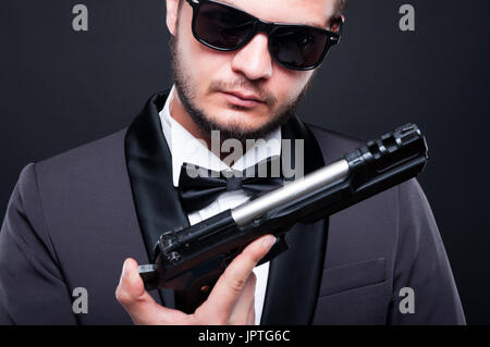 Serious undercover criminal wearing an elegant suit and loading a gun in closeup view Stock Photo