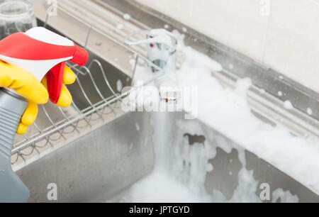 Woman washing the sink and tap with disinfecting spray in closeup