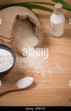 Jasmine white rice in sack and rice flour on wooden table. Stock Photo