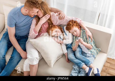 High angle view of beautiful redhead family lying together on sofa, big family portrait Stock Photo