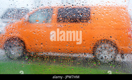 Looking through a raindrop covered window at houses on a rainy summers day Stock Photo