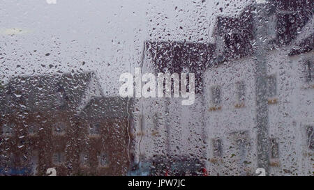 Looking through a raindrop covered window at houses on a rainy summers day Stock Photo