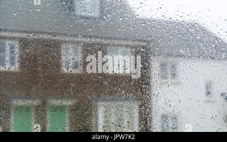 Looking through a raindrop covered window at houses on a rainy summers day Stock Photo