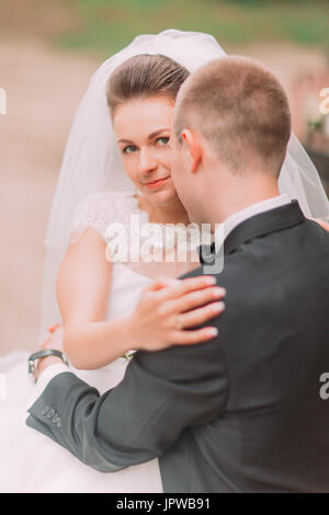The close-up portrait of the pretty bride hugging with the groom. Stock Photo
