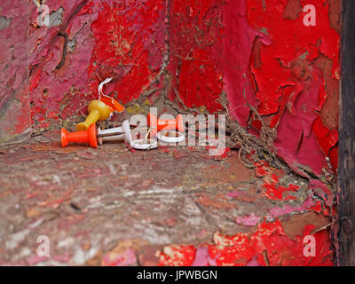 plastic coated pin tacks and drawing pins on flaking red painted windowsill in Cumbria,England UK Stock Photo