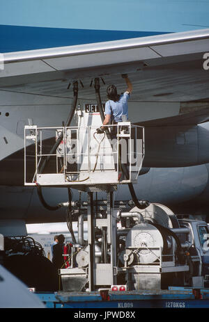 refueller monitoring two fuel-hoses attached to the underside of the wing of a KLM Boeing 747-400 parked Stock Photo