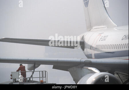 refueller monitoring a fuel-hose attached to the underside of the wing of a China Northwest Airlines Airbus A310-200 parked Stock Photo