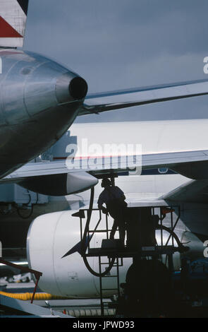 refueller with a fuel-hose attached to the underside of the wing of a Boeing 767-200 parked with an APU exhaust outlet Stock Photo