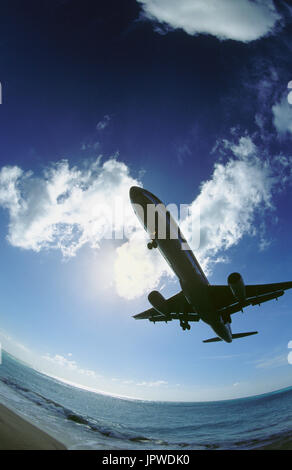 American Airlines Boeing 757-200 on very low final-approach over Maho Beach with sun behind clouds Stock Photo