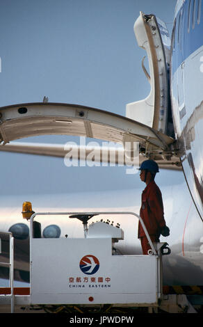 man standing waiting to start loading cargo next to open side cargo door of a Boeing 747-200 Stock Photo