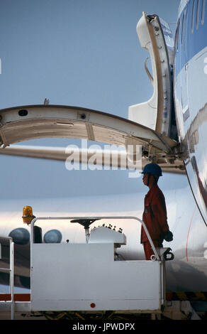 man standing waiting to start loading cargo next to open side cargo door of a Boeing 747-200 Stock Photo