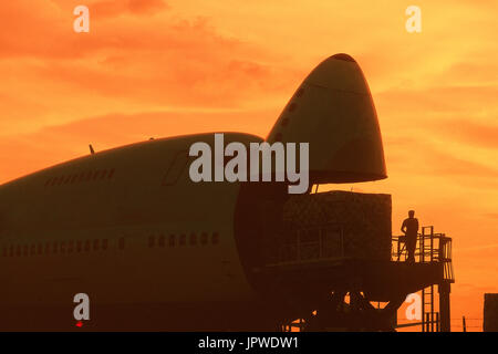 cargo being loaded into open nose cargo door of a Southern Air Transport Boeing 747 at dusk Stock Photo