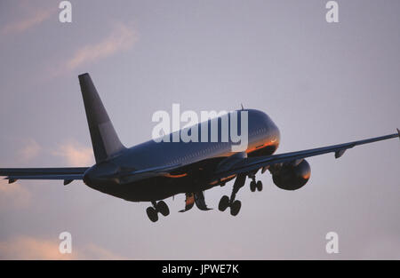 generic Airbus A320-200 climbing out after take-off with undercarriage retracting at dusk Stock Photo