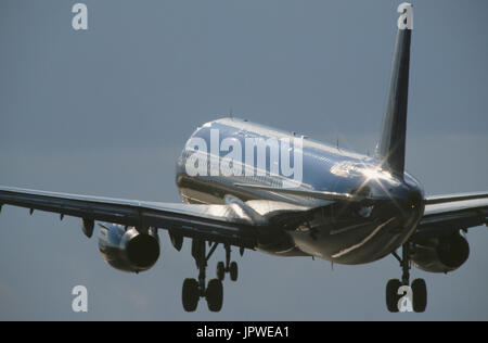 generic Airbus A321-200 on final-approach with flaps deployed and sun glinting off the fuselage and wings Stock Photo