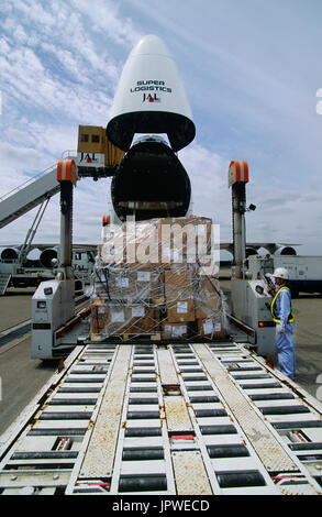 cargo being loaded from a low-loader into the open cargo door into the nose of a Japan Airlines Cargo Boeing 747 parked Stock Photo