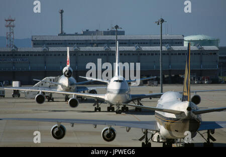 Singapore Airlines Boeing 747-400 being pushed-back by a tug with a JAL Boeing 747-400 taxiing and McDonnell Douglas DC-10-40 parked at the terminal b Stock Photo