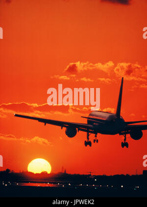 Boeing 757 landing on the runway at sunset with runway-lights on Stock Photo