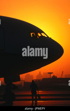 marshaller and nose of an ANA Boeing 767-300 with pilot in the cockpit at dusk Stock Photo