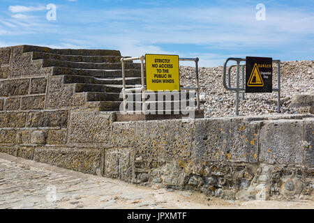 Strictly no access to the public in high winds sign and danger unguarded drop sign on steps leading to the Cobb at Lyme Regis, Dorset UK in July Stock Photo