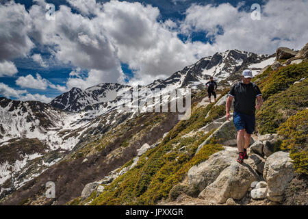 Spectacular clouds over Monte Renoso summit, on right, two hikers on GR 20 trail variant near Capannelle mountain huts, Haute-Corse, Corsica, France Stock Photo