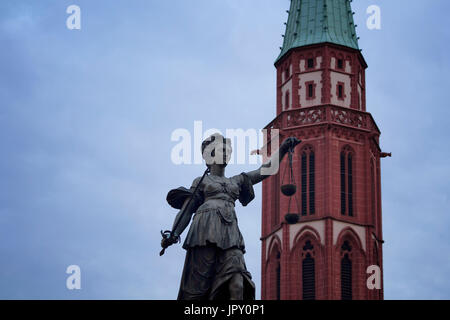 View of a statue of justice at Romerberg historical market square in Frankfurt. Alte Nikolaikirche gothic church dating to the middle ages in the back Stock Photo