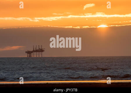 Sunsetting in Ainsdale, Southport, Merseyside, UK. 2nd August 2017. UK Weather. A colourful sunset over Morecambe Bay Gas Rig. In 1974, the second-largest gas field in the UK was discovered 25 miles (40 km) west of Blackpool. Its original reserves were over 7 trillion cubic feet (tcf) (200 billion cubic metres). At its peak, 15% of Britain's gas supply came from the bay, but production is now in decline, and the main field was mothballed in 2011. Stock Photo