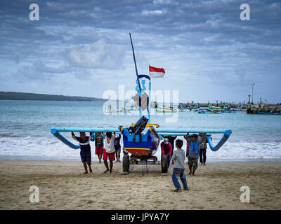 Kuta, Bali, Indonesia. 3rd Aug, 2017. Men push their outrigger fishing canoes up onto Jimbrana Beach in Kuta after a night of fishing on the Indian Ocean. The beach is close to the airport and a short drive from other beaches in southeast Bali. Jimbrana was originally a fishing village with a busy local market. About 25 years ago, developers started building restaurants and hotels along the beach and land prices are rising. The new emphasis on tourism is changing the nature of the area but the fishermen are still busy very early in the morning. Credit: Jack Kurtz/ZUMA Wire/Alamy Live News Stock Photo