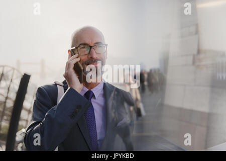 Businessman talking on cell phone on urban street Stock Photo