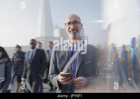 Portrait confident businessman listening to music with cell phone and headphones on busy urban street Stock Photo