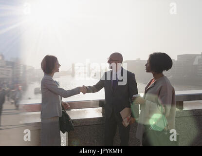 Silhouette business people handshaking on sunny urban bridge over Thames River, London, UK Stock Photo