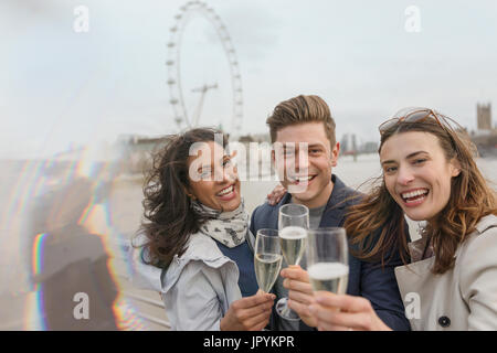 Portrait enthusiastic, smiling friends celebrating, toasting champagne near Millennium Wheel, London, UK Stock Photo