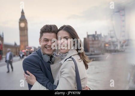 Portrait smiling couple tourists hugging in front of Big Ben, London, UK Stock Photo