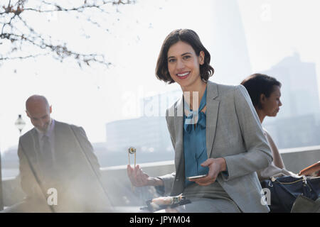 Portrait smiling businesswoman eating sushi on lunch break in sunny urban park Stock Photo